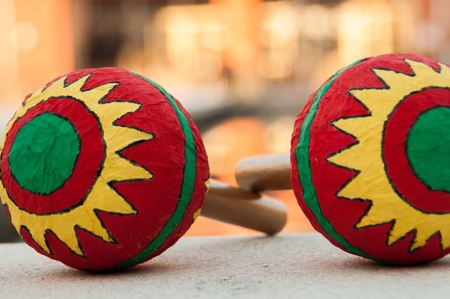 Due maracas dipinte a mano con un sole rosso, giallo e verde, appoggiate su un muretto